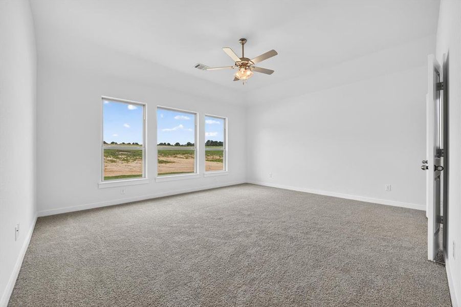 Spacious room featuring light-toned carpeting, white walls, and three large windows offering expansive outdoor scenery