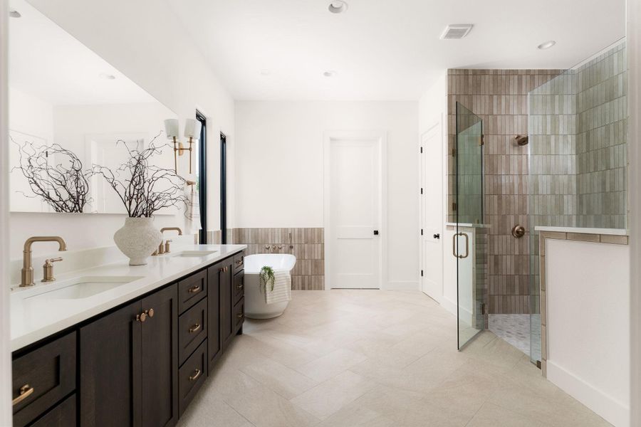 A grand bath offers dual vanities, a soaking tub, and a spacious glass-enclosed shower.