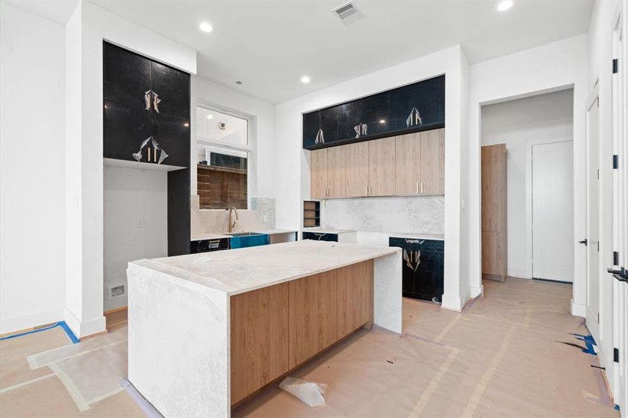 Kitchen design includes quartz waterfall island, engineered white oak hardwood floors and dry bar.