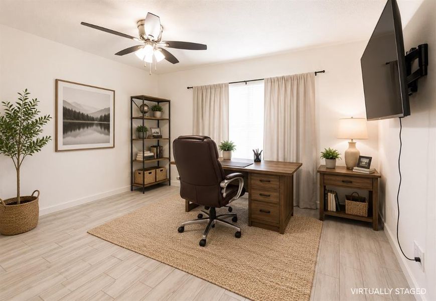 Spacious room featuring light wood-finish flooring, a ceiling fan with integrated lighting, and a window with neutral drapes