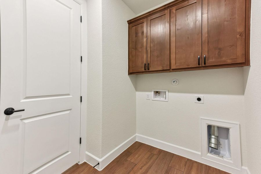 Laundry area with dark wood-style flooring, washer hookup, hookup for an electric dryer, cabinet space, and a textured wall
