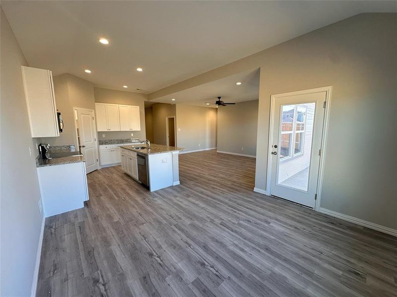 Kitchen featuring white cabinets, sink, wood-type flooring, ceiling fan, and a kitchen island with sink