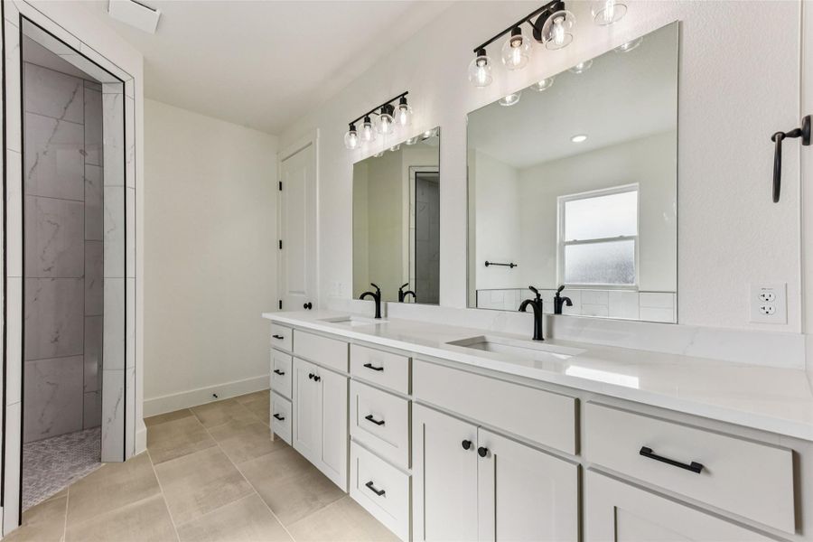 Bathroom with double vanity, a marble finish shower, and light tile patterned flooring