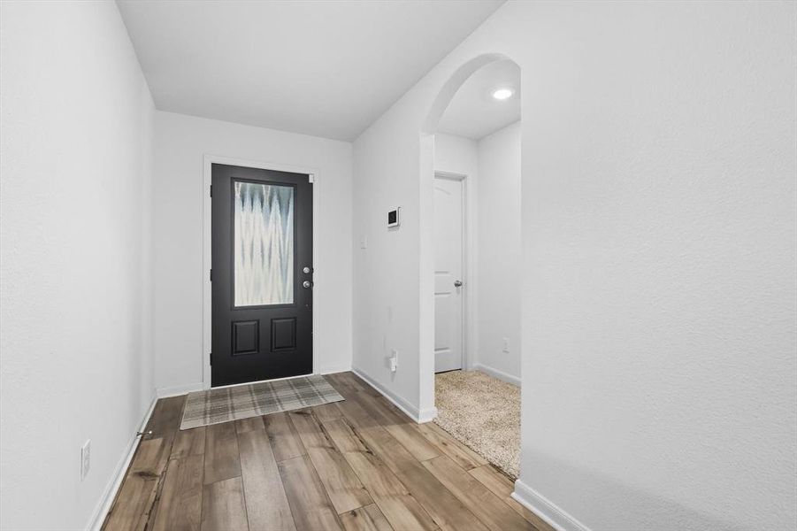 Entrance foyer with wood finished floors and arched walkways