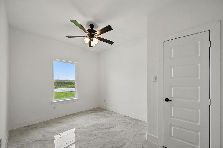 Empty room with light marble finish floors and a ceiling fan