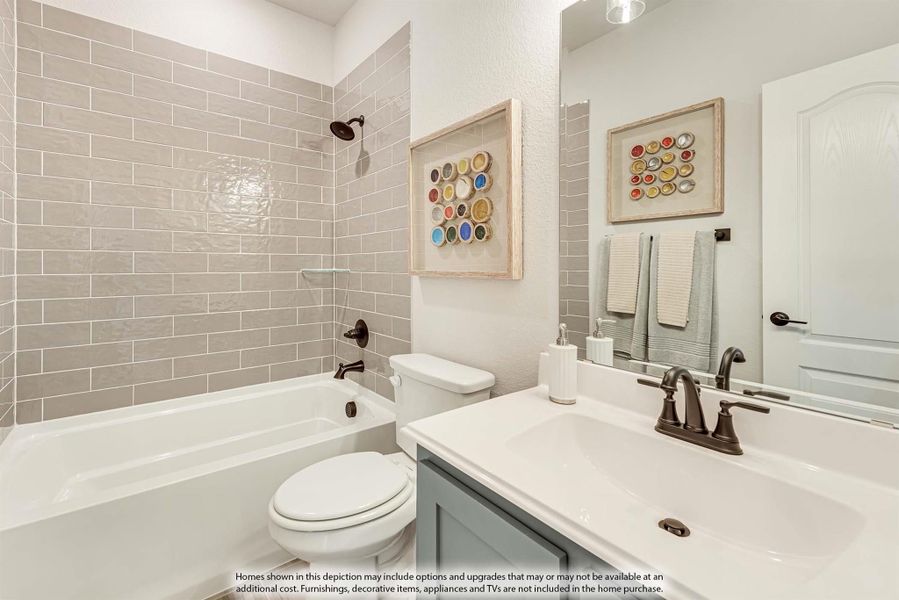 Bathroom with gray subway tile tub surround, white vanity with dark faucet, and toilet
