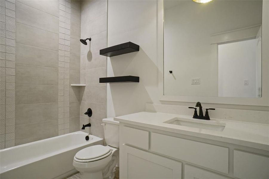 Full bathroom with toilet, tiled shower / bath, and vanity with extensive cabinet space