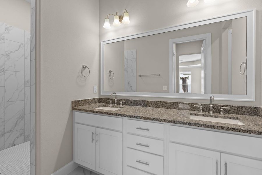The primary bathroom features dual sinks, a spacious vanity, and a luxurious shower and tub combination—perfect for unwinding at the end of the day. Image depicts home as-is.