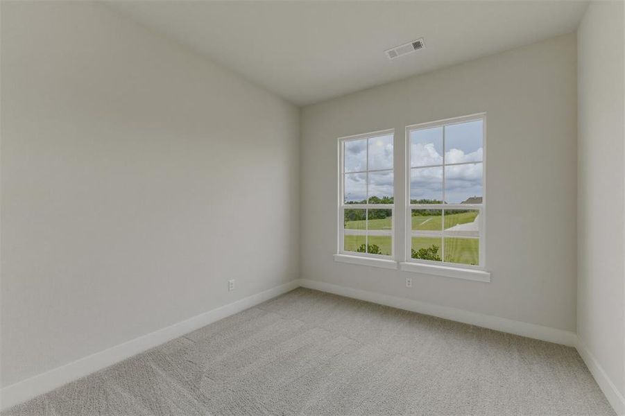 Interior room featuring light-toned walls, gray carpet flooring, white baseboards, and two multi-pane windows with white trim Interior room featuring light-toned walls, gray carpet flooring, white baseboards, and two multi-pane windows with white trim