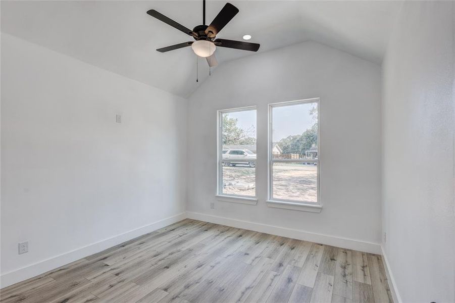 Spare room with vaulted ceiling, light hardwood / wood-style flooring, and ceiling fan