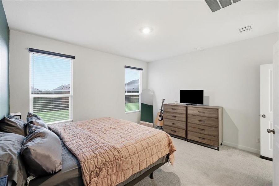 Bright bedroom featuring plush carpet flooring and two windows with blinds Bright bedroom featuring plush carpet flooring and two windows with blinds