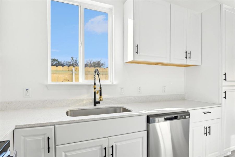 Kitchen featuring a sink, white cabinetry, light countertops, and stainless steel dishwasher