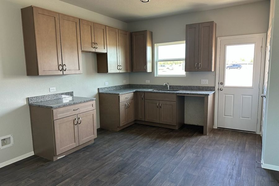 Image of home kitchen with light brown cabinets, wood-look floors, and window on rear door and over sink