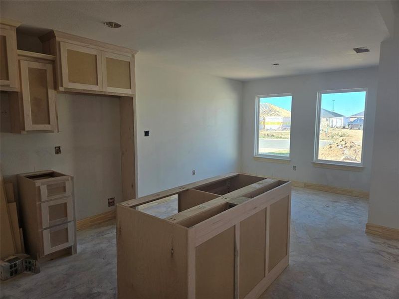 Kitchen with light brown cabinets, a center island, and concrete floors