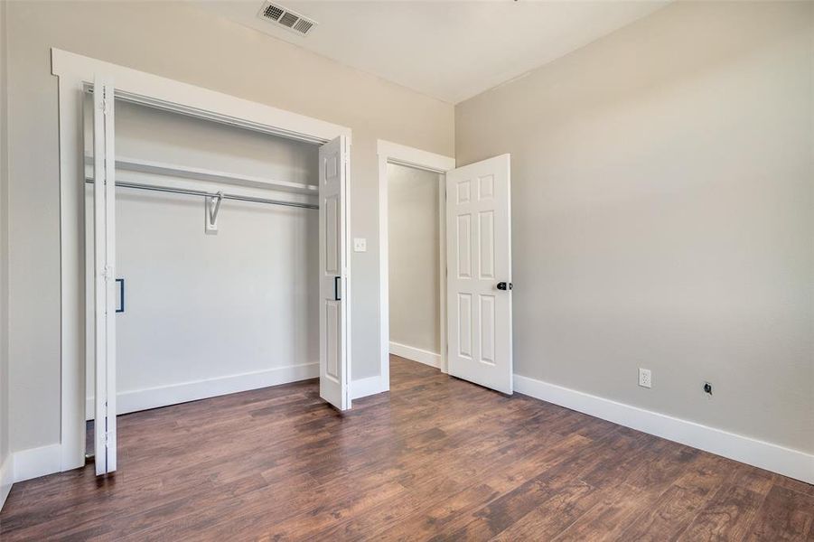 Unfurnished bedroom with dark hardwood / wood-style floors and a closet