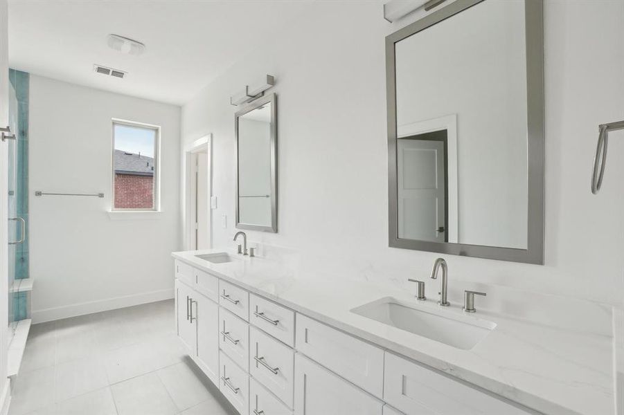 Bathroom with baseboards, double vanity, a stall shower, and tile patterned flooring