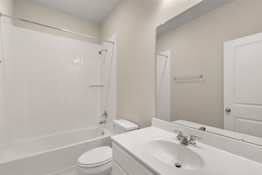 The secondary bath features tile flooring, white cabinetry and light countertops and a shower/tub combo. Perfect for accommodating any visiting family and friends.