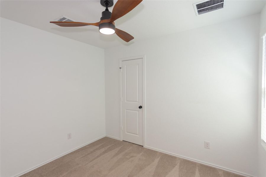Room featuring a modern ceiling fan with wood-finish blades and integrated lighting, neutral carpet flooring, white walls, and a window with horizontal blinds