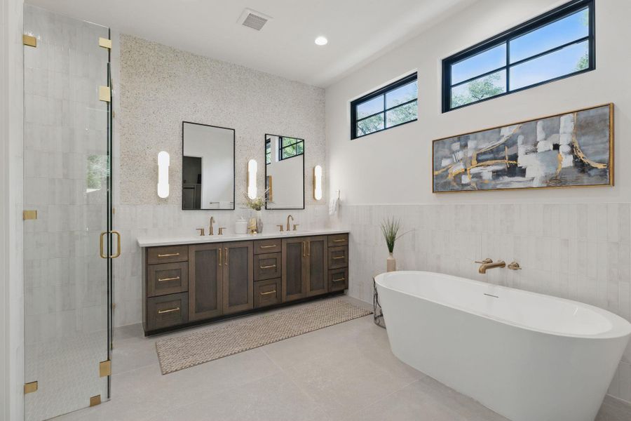 Bathroom with tile walls, double vanity, a stall shower, a freestanding bath, and tile patterned flooring