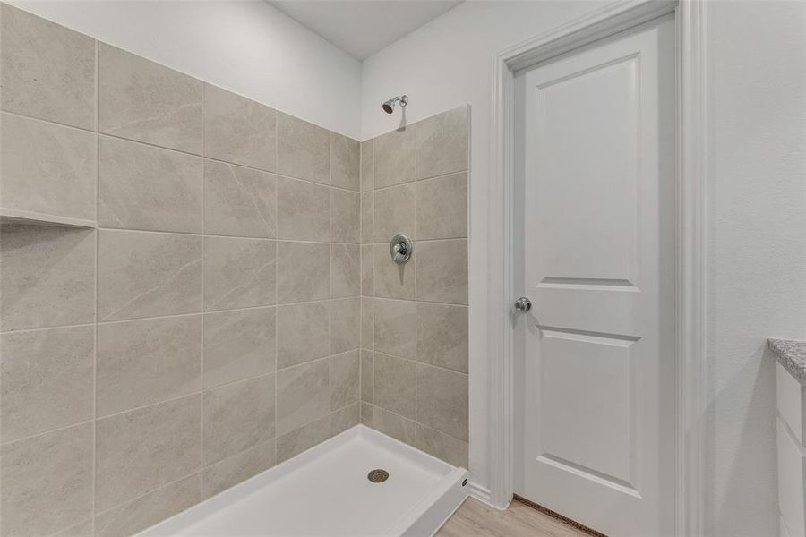 Bathroom with a tile shower and hardwood / wood-style flooring