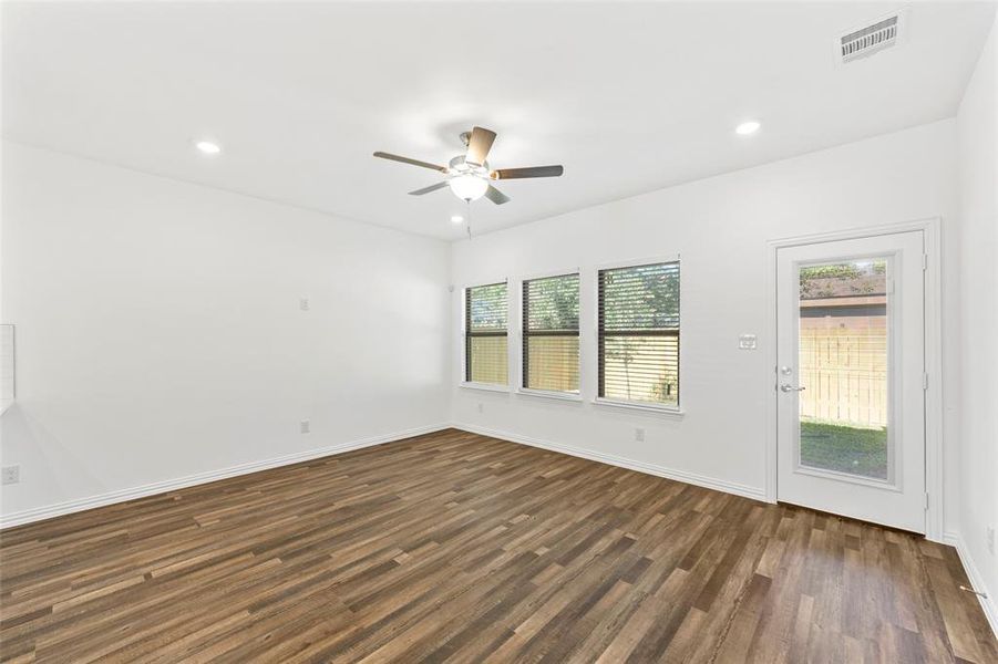 Empty room featuring ceiling fan, plenty of natural light, and dark hardwood / wood-style flooring