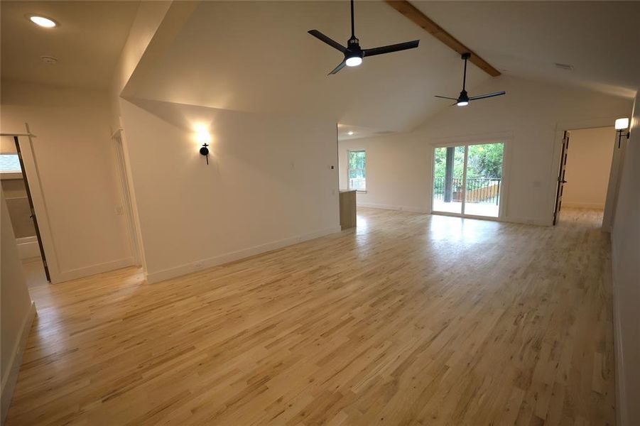 Spare room with light wood floors, beamed ceiling, a ceiling fan, and high vaulted ceiling