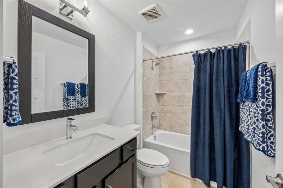 And this is just outside of the 4th secondary bedroom.  So most convenient for guests to use.  Stylish glass and chrome vanity light fixtures replacing builder-grade lighting and wood framed mirror.