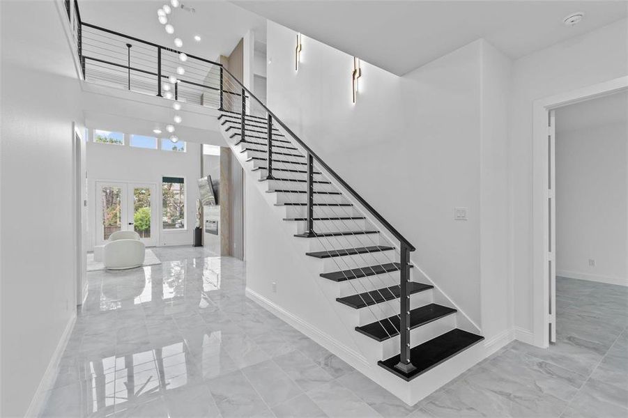 Stairs featuring french doors, marble tiled floors, and a high ceiling