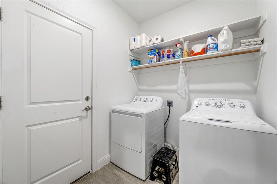 Washroom with independent washer and dryer and light wood-type flooring