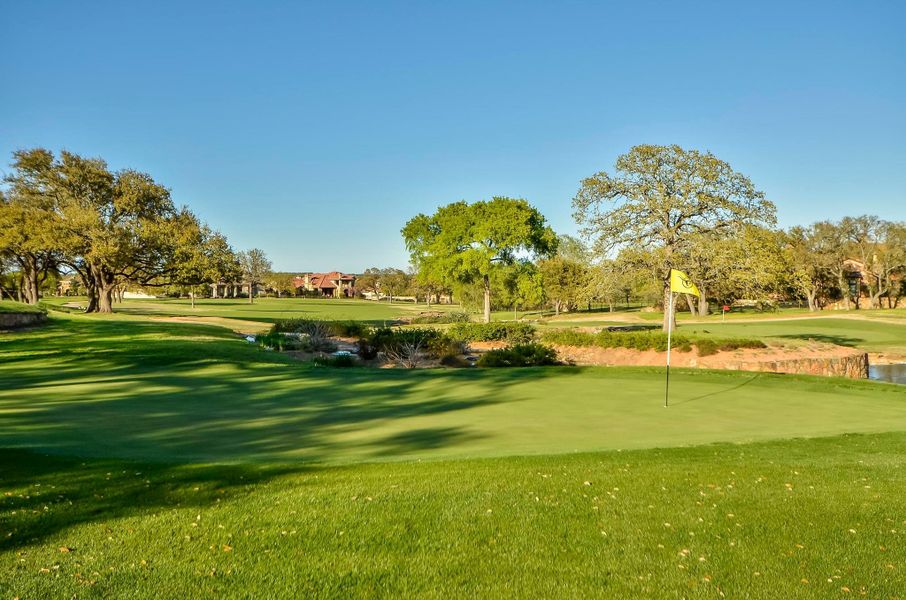 Surrounding community with golf course view, a lawn, and a putting area