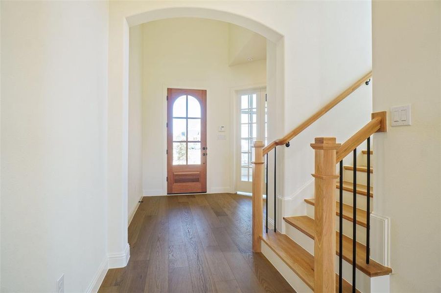 Foyer entrance featuring arched walkways, dark wood finished floors, and stairs Foyer entrance featuring arched walkways, dark wood finished floors, and stairs