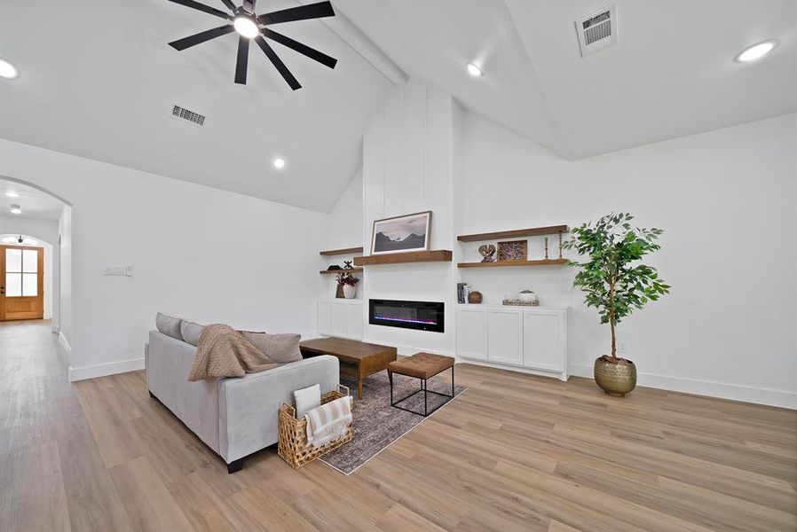 Living area featuring a vaulted ceiling with a modern ceiling fan, recessed lighting, and wood-finish flooring Living area featuring a vaulted ceiling with a modern ceiling fan, recessed lighting, and wood-finish flooring