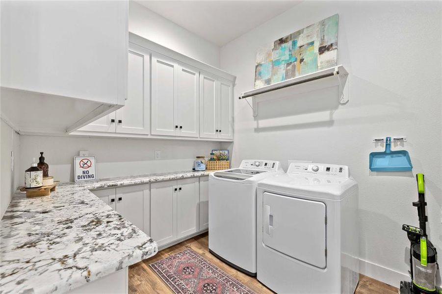 Washroom featuring cabinet space, washer and clothes dryer, and light wood-style floors