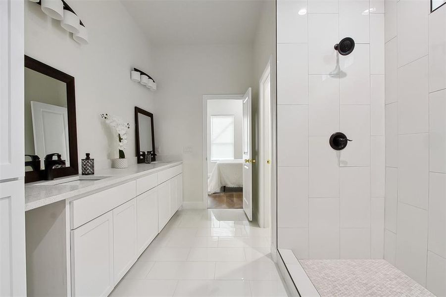 Bathroom featuring tile patterned flooring, vanity, and tiled shower