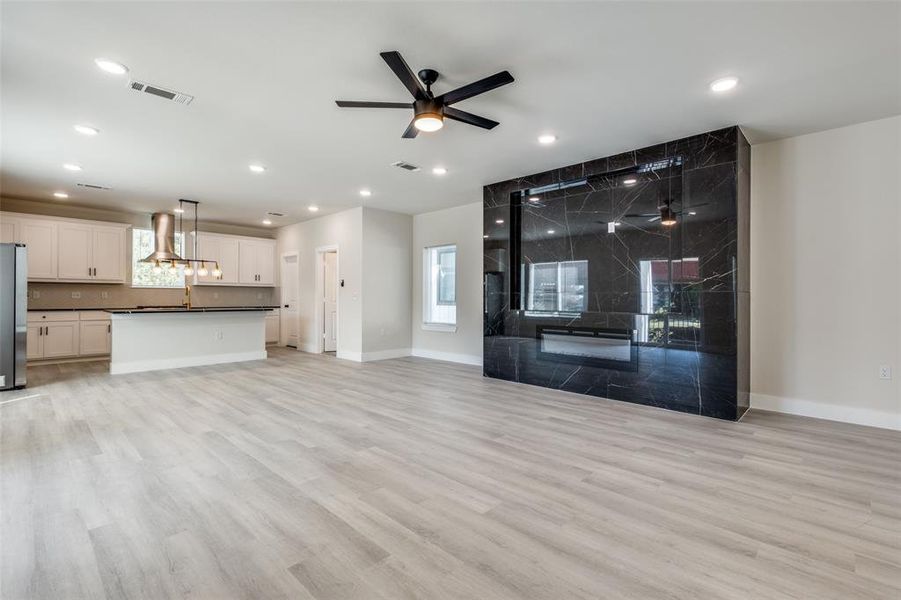 Unfurnished living room with a ceiling fan and light wood-type flooring
