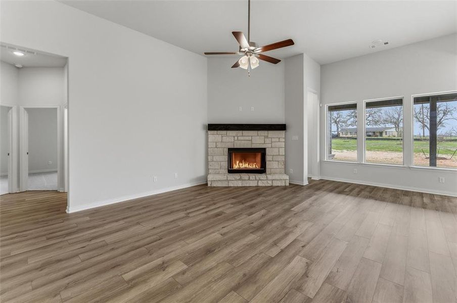 Unfurnished living room with a fireplace, a ceiling fan, and light wood-style flooring