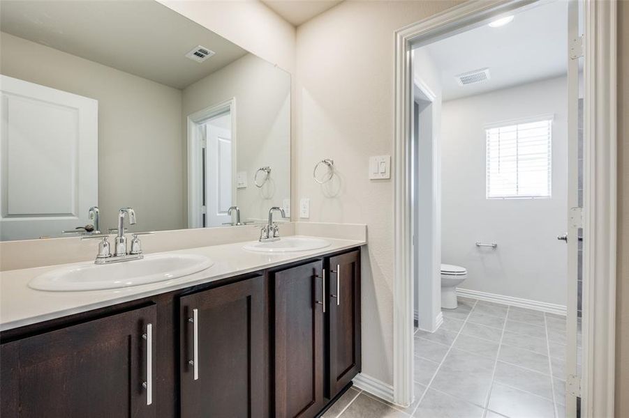 Bathroom with dual vanity, tile patterned flooring, and toilet