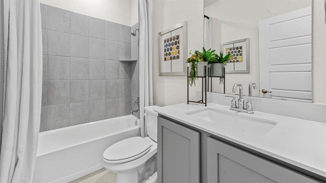 Bathroom featuring a tub/shower combination with grey tile surround and built-in niche