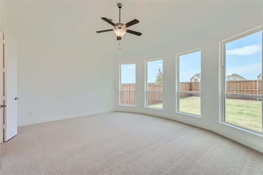 Carpeted spare room featuring a high ceiling and ceiling fan