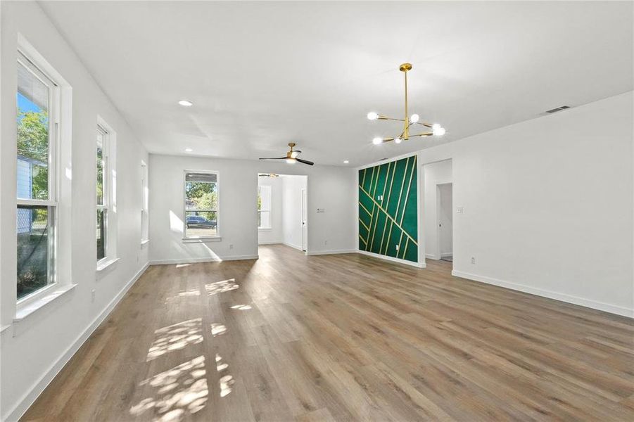 Unfurnished living room with light hardwood / wood-style floors and ceiling fan with notable chandelier