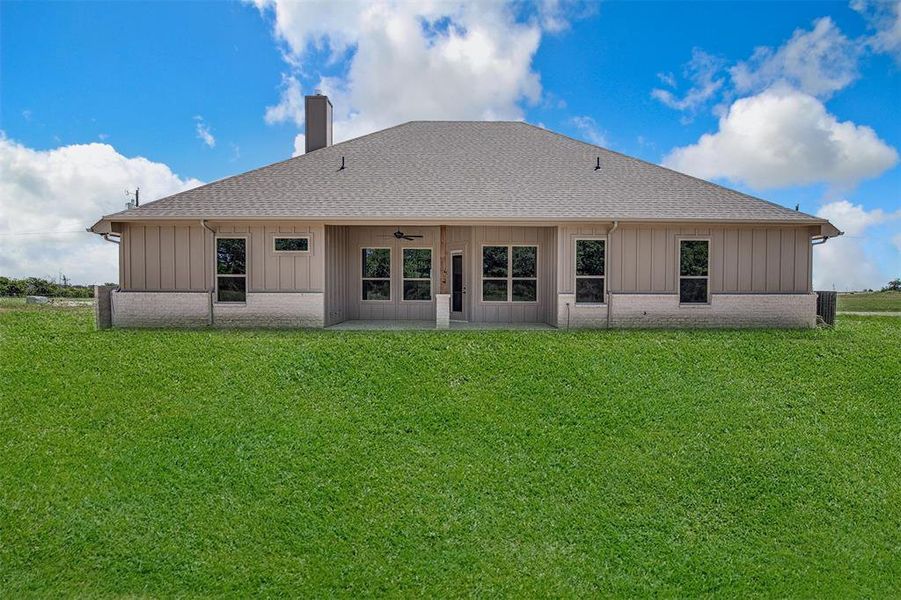 Back of property with ceiling fan and a yard