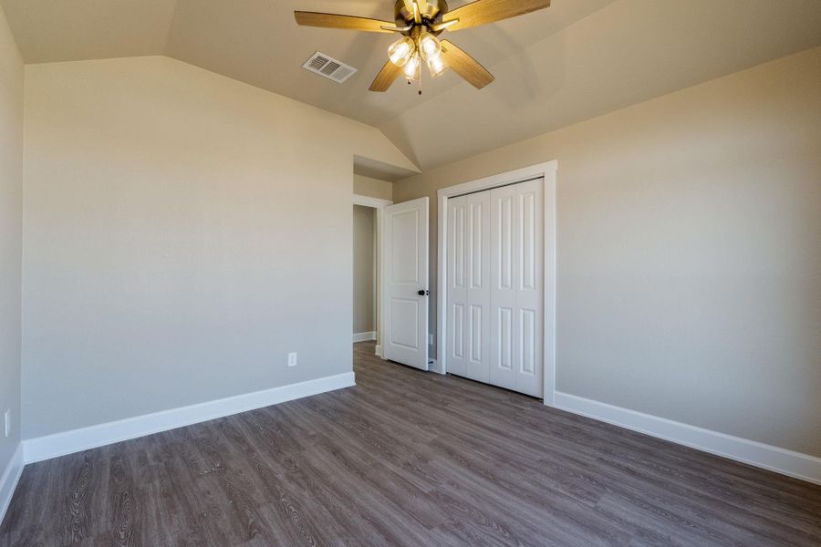 Unfurnished bedroom with vaulted ceiling, dark wood-style floors, ceiling fan, and a closet