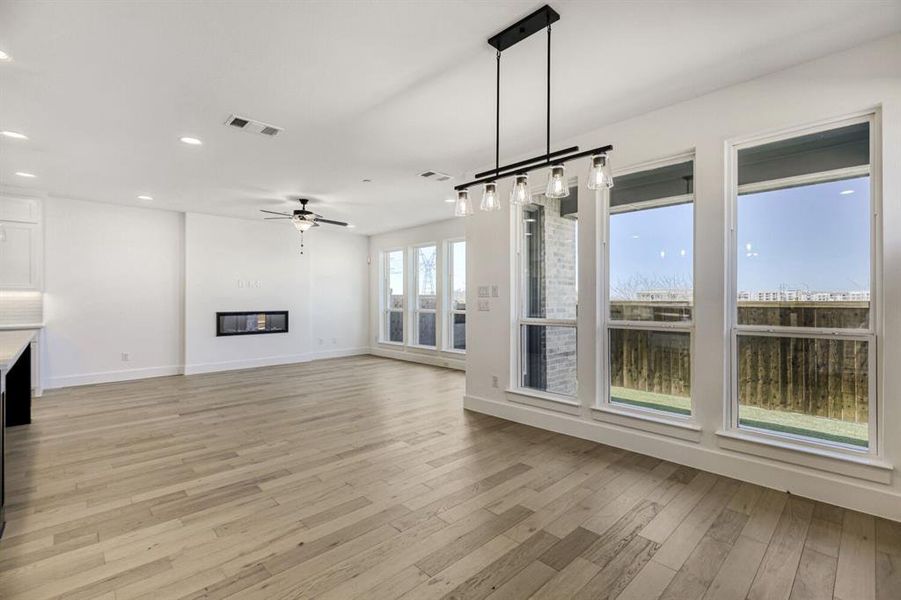 Unfurnished living room with a glass covered fireplace, a ceiling fan, recessed lighting, and light wood-style flooring