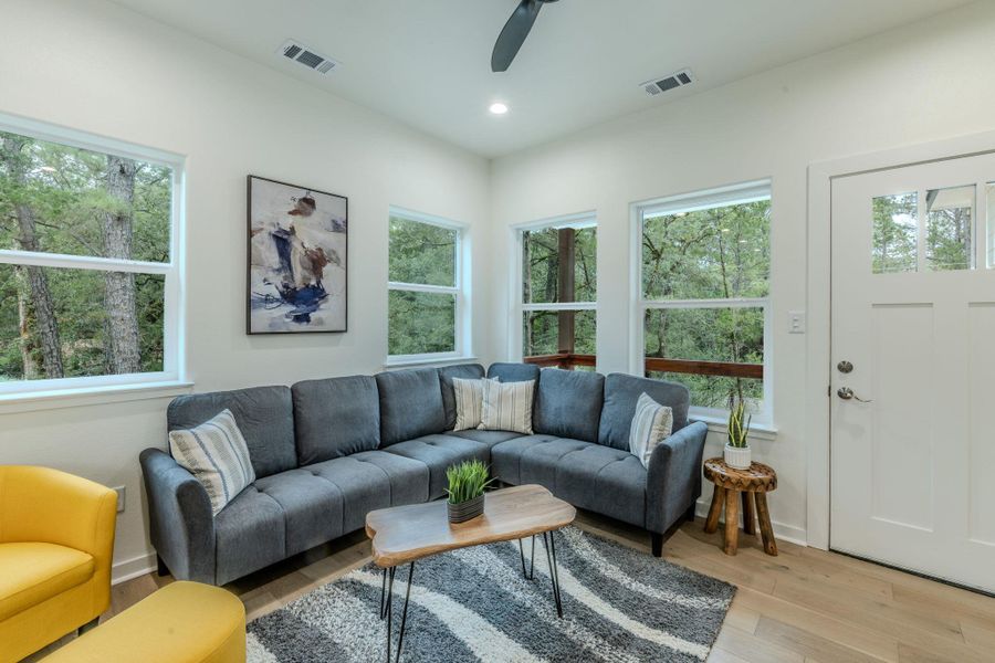 A well-lit living area with ample natural light from numerous windows and warm hardwood flooring. A well-lit living area with ample natural light from numerous windows and warm hardwood flooring.