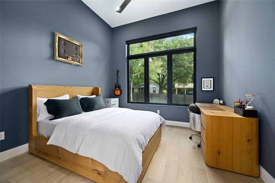 Bedroom featuring lofted ceiling, light wood-style flooring, and baseboards