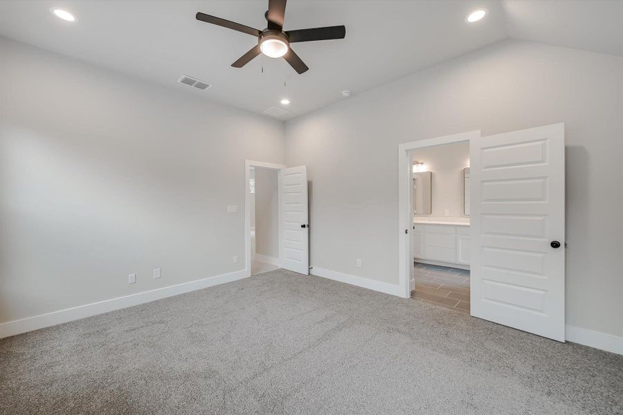 Unfurnished bedroom with lofted ceiling, recessed lighting, light colored carpet, visible vents, and baseboards