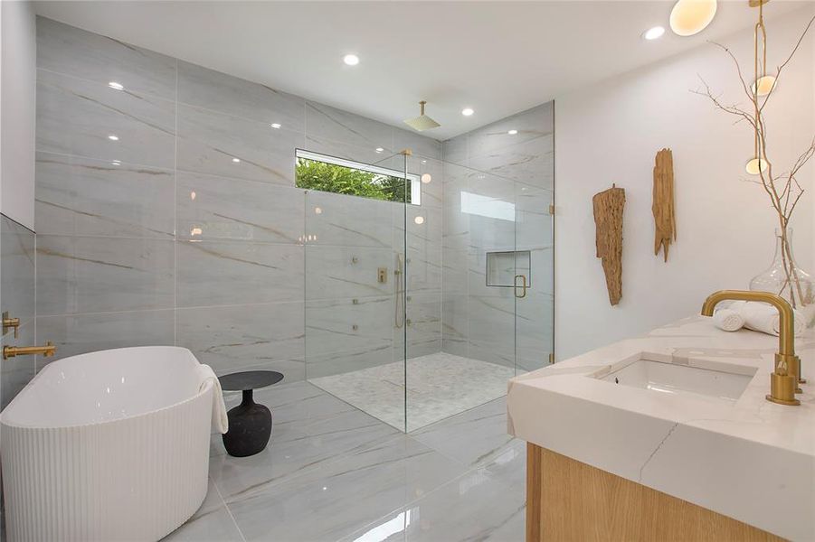 Bathroom featuring shower with separate bathtub, vanity, and tile walls