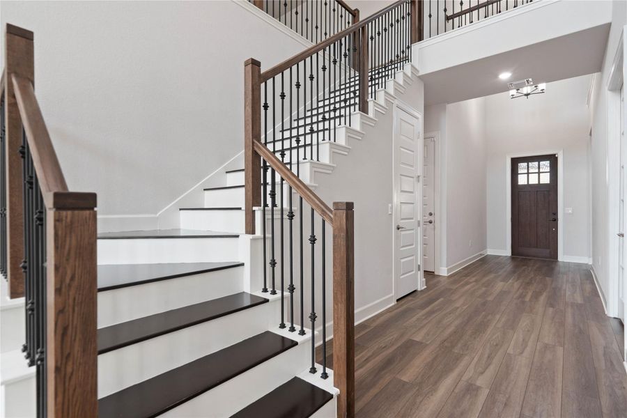 Rich wood floors and a grand staircase create a welcoming first impression.