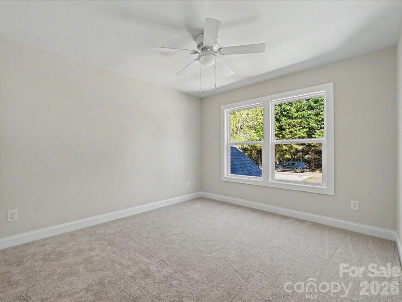 Spacious secondary bedroom features soft carpeting, abundant natural light, and a neutral palette ready for guests or personalization.