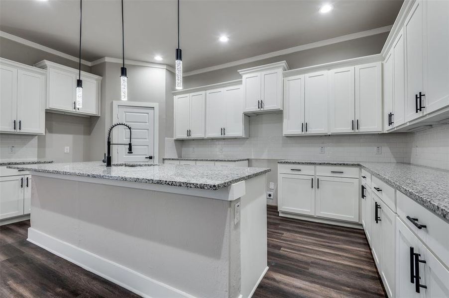 Kitchen with recessed lighting, decorative backsplash, white cabinets, and ornamental molding Kitchen with recessed lighting, decorative backsplash, white cabinets, and ornamental molding